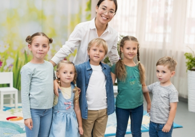 smiley-teacher-holding-her-students-at-kindergarten